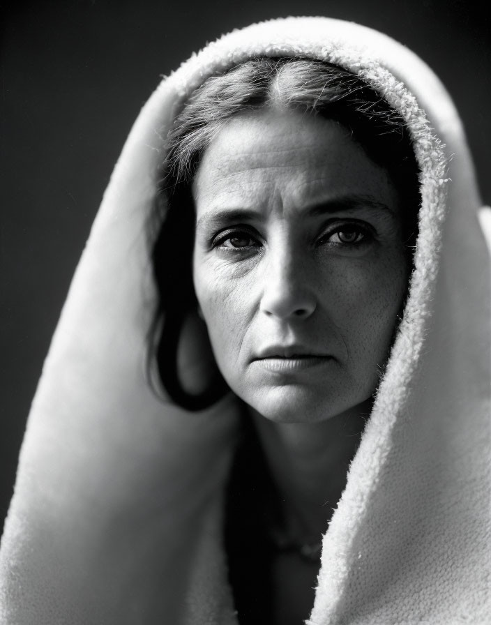 Monochrome portrait of contemplative woman with draped cloth and gazing eyes