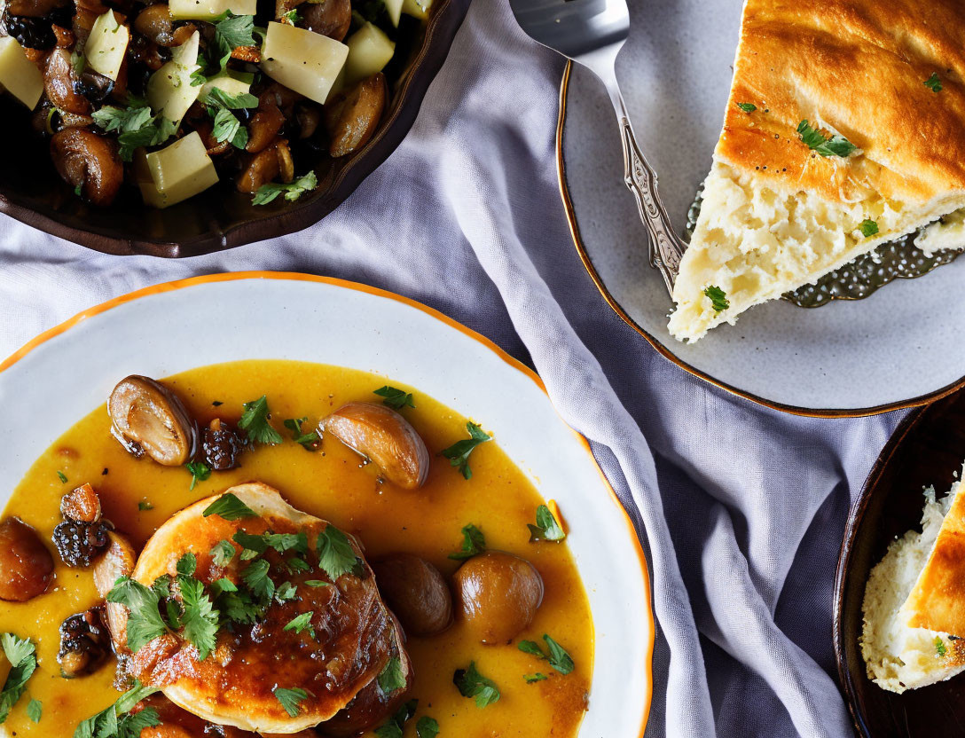 Plated chicken dish with orange sauce, mushrooms, herbs, vegetables, and herbed bread