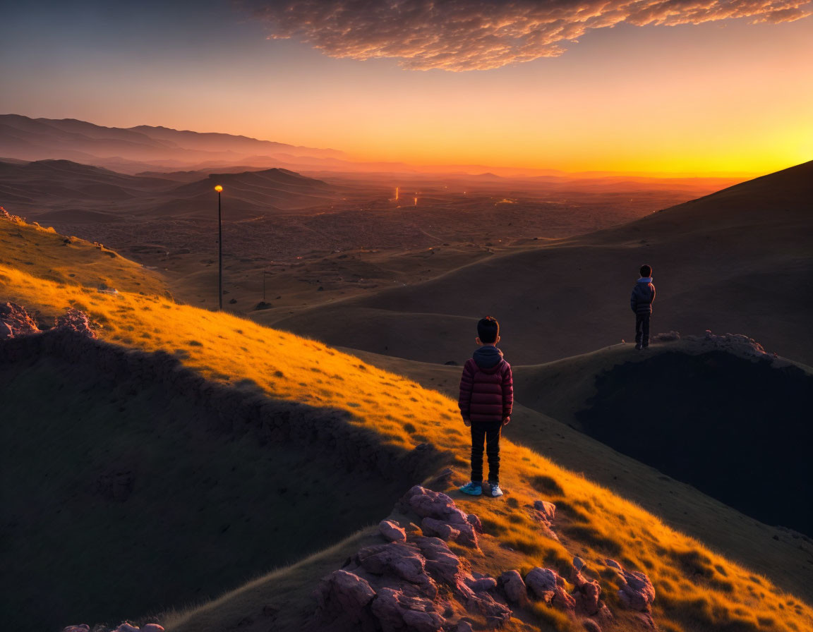 Sunset scene with two individuals on grassy hill overlooking valley