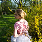 Woman in white vintage dress in garden at sunset with sunlight filtering through trees