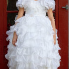 Person in white gown with sugar skull makeup, surrounded by Day of the Dead decor.