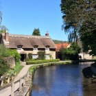 Thatched cottage by serene river amidst lush greenery