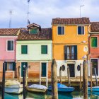 Vibrant canal houses and boats under blue sky with clouds