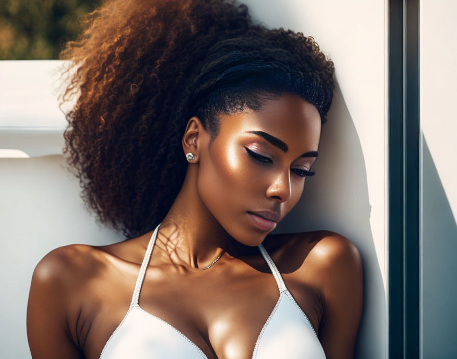 Curly-haired woman in white top under sunlight