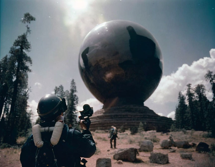 Astronaut in spacesuit with camera by reflective sphere in forest