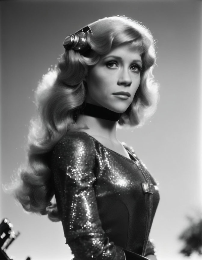 Monochrome image: Woman with curly blonde hair in sparkling attire and headset.