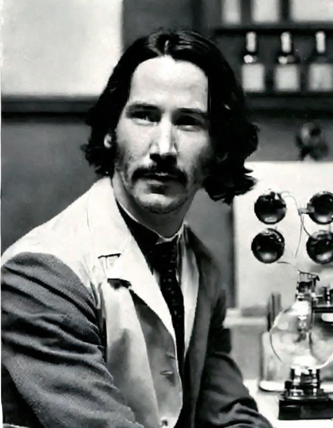 Monochrome photo: man with mustache, long hair, light jacket, in vintage room with equipment