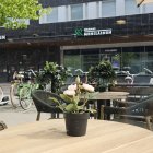 Tranquil outdoor scene with wooden table, ceramic vases, plant, hills, and river