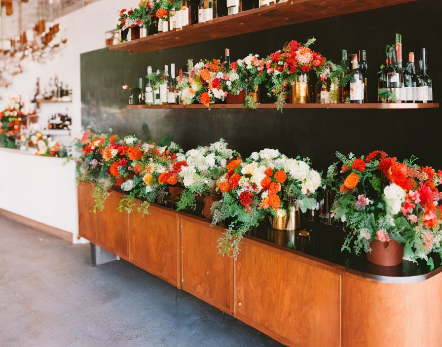 Bar counter decorated with vibrant flowers and assorted liquor bottles