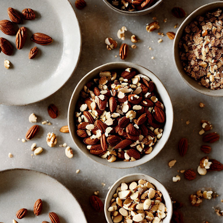 Assorted Nuts and Granola Bowls on Textured Gray Surface