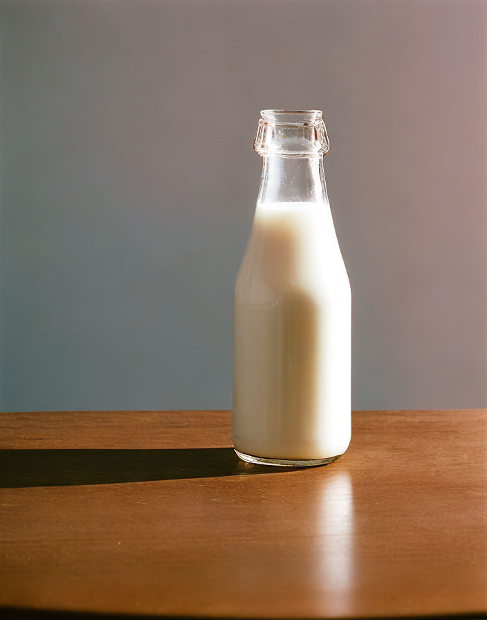 Traditional Glass Milk Bottle on Wooden Surface against Neutral Background