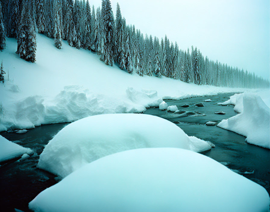 Snow-covered landscape with river, pine trees, misty atmosphere