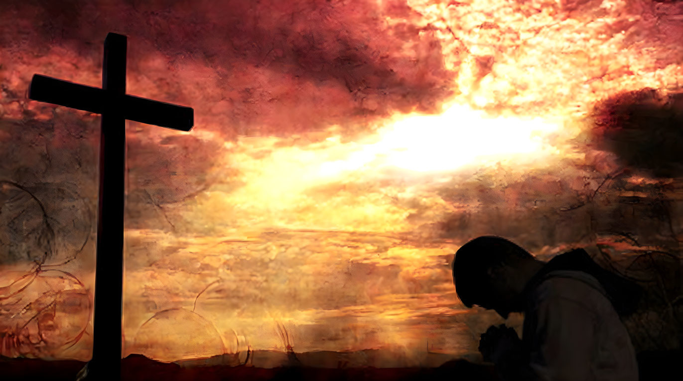 Silhouette of person praying before cross at fiery sunset.