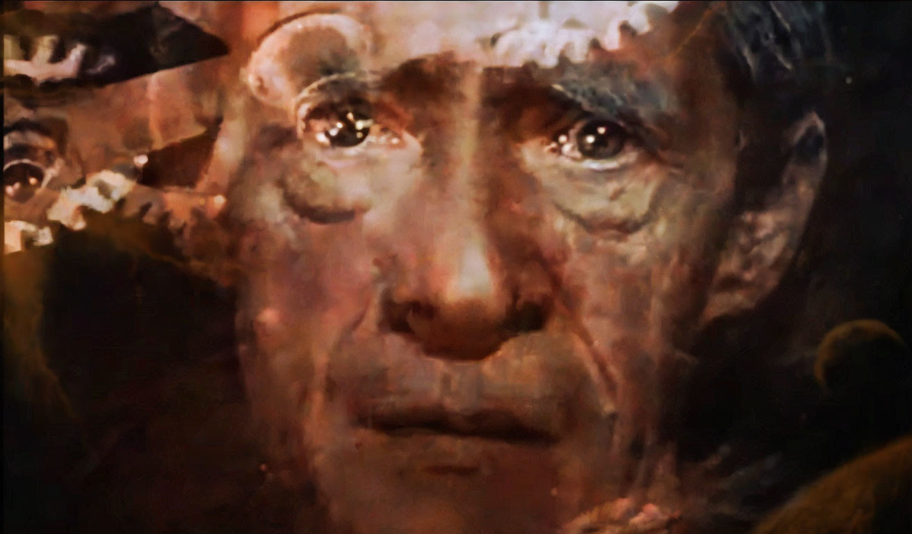 Close-up of distressed man's face with fiery, chaotic imagery.