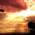 Silhouette of person praying before cross at fiery sunset.