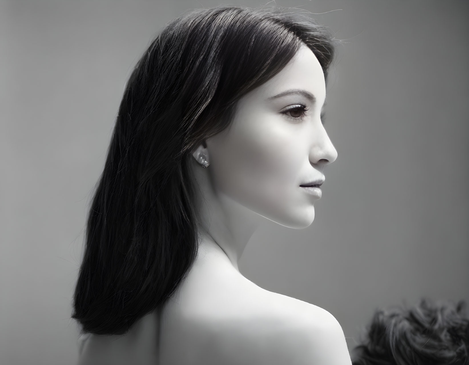 Portrait of woman with long dark hair and earrings on grey background