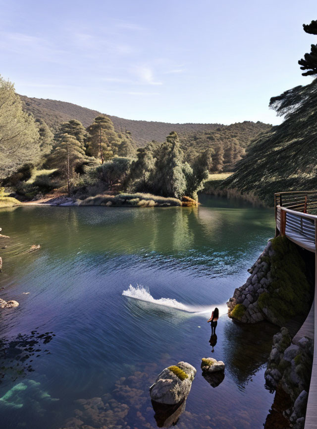 Person diving into clear river amidst lush greenery and rocky terrain