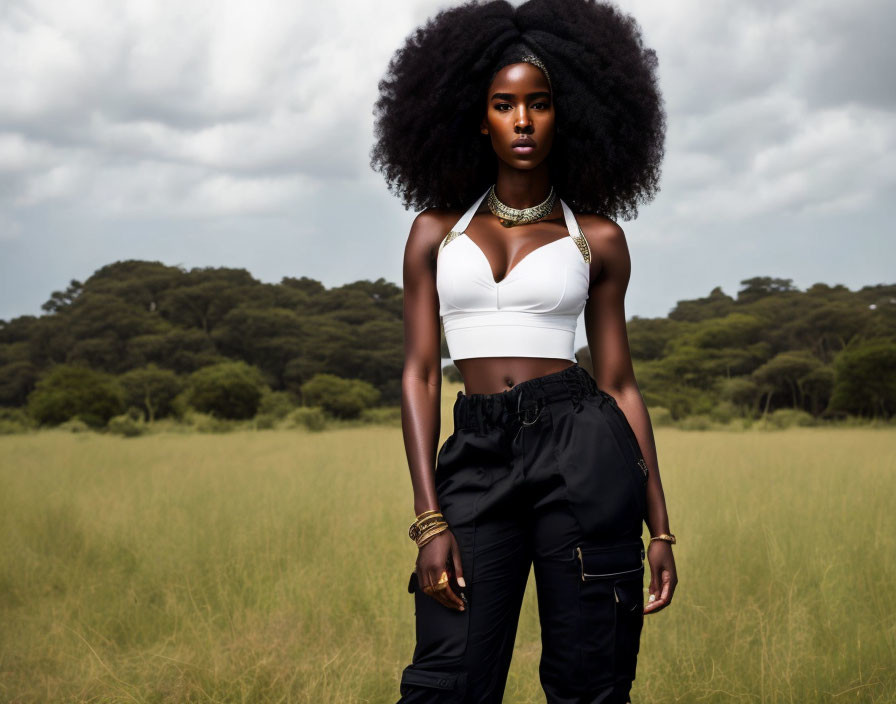 Woman with voluminous afro hair in white crop top and cargo pants in field