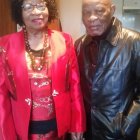 Regal Couple in Pink Traditional Attire and Grey Suit with African Accents