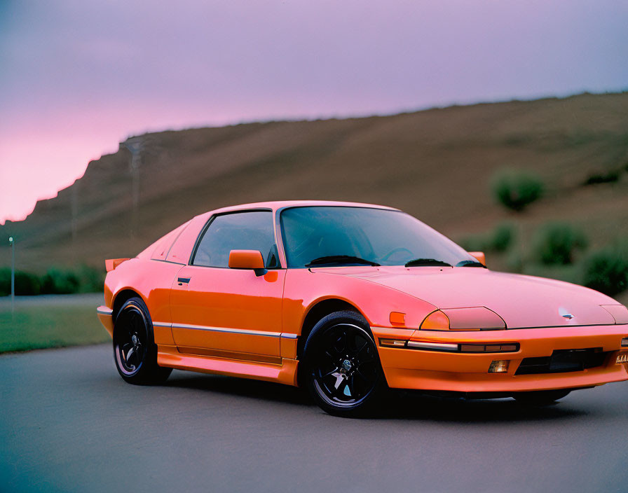 Vintage Orange Sports Car Parked Outdoors at Sunset