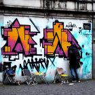 Vibrant graffiti wall with two people, one hiding face.