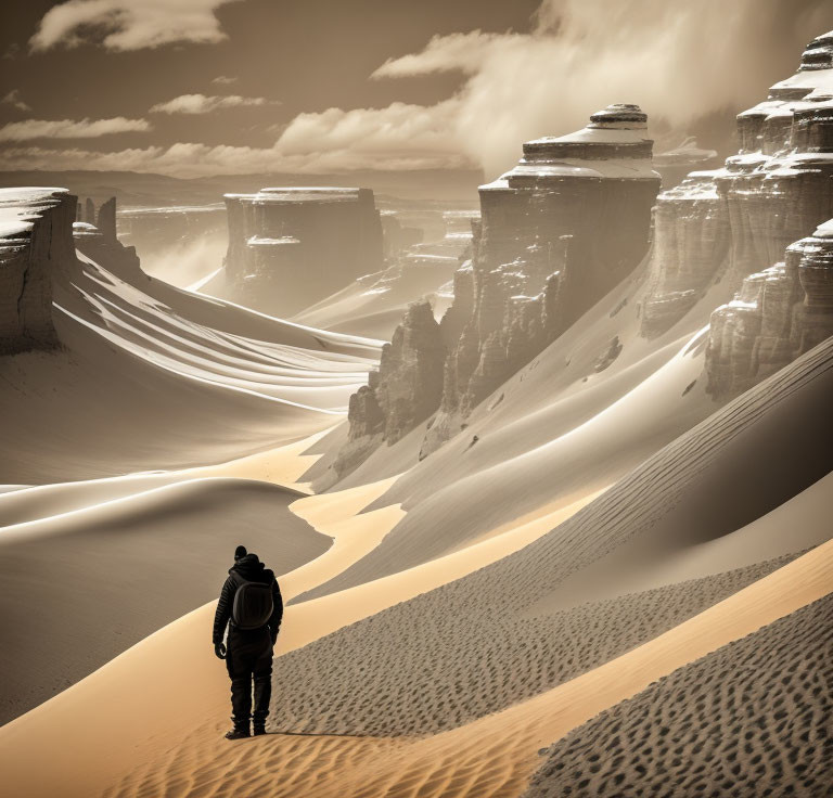 Solitary figure in vast desert dunes with towering sandstone cliffs