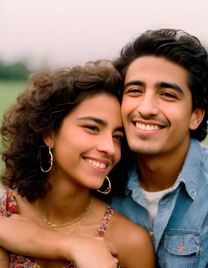 Smiling young couple embracing outdoors in denim shirt and floral dress