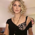 Blonde woman in black floral dress with cityscape and chandelier.