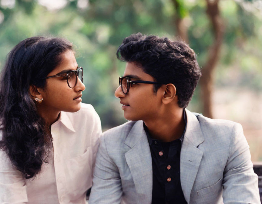 Two people wearing glasses in a nature setting.