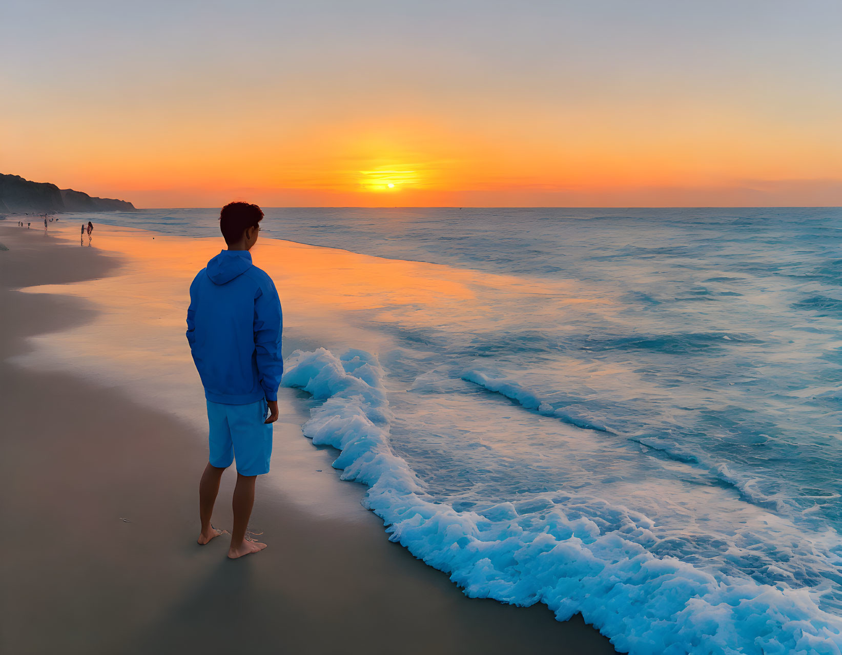 Person in Blue Hoodie Admiring Sunset on Beach