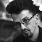 Monochrome illustration of young man with curly hair and glasses in bar setting