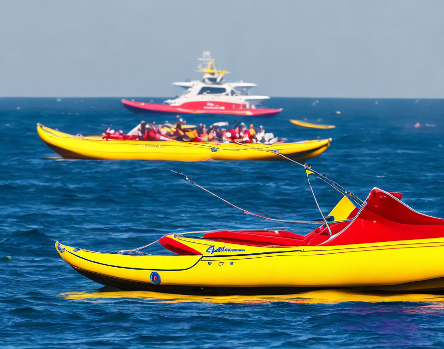 Banana boats and pedal boat on calm sea with yacht in background