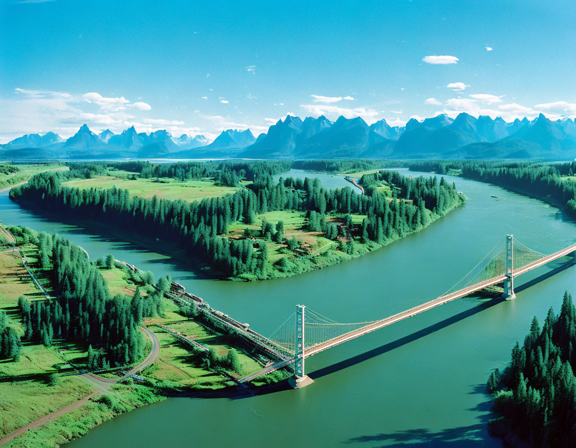 Scenic suspension bridge over winding river with lush greenery & mountain peaks in background