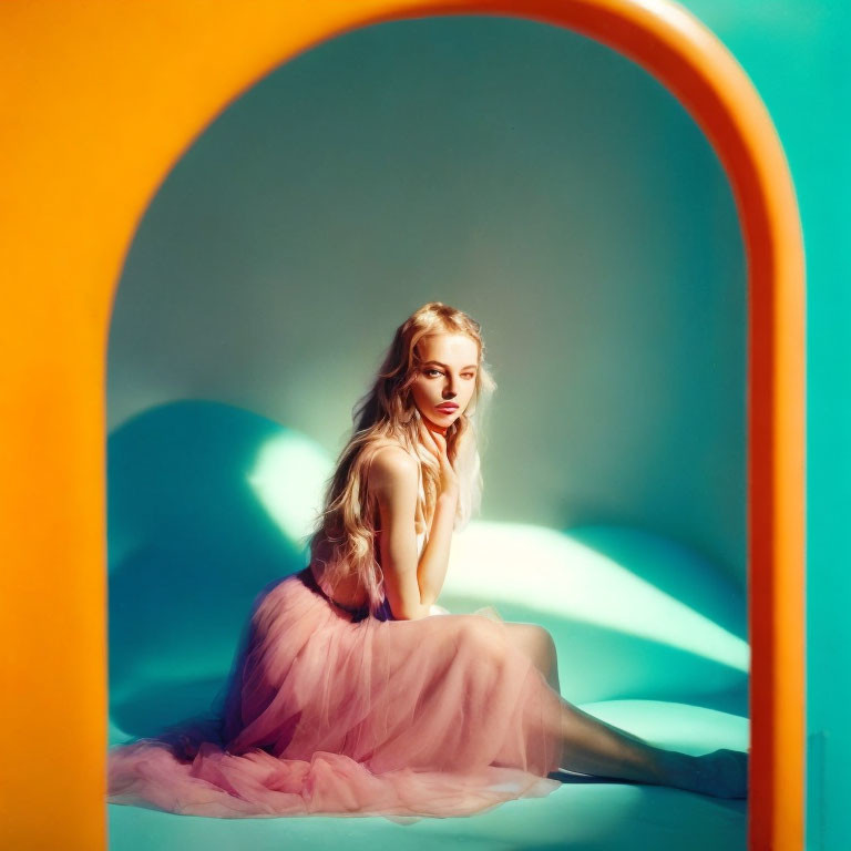 Blonde woman in pink tulle dress under arch with warm and cool lighting