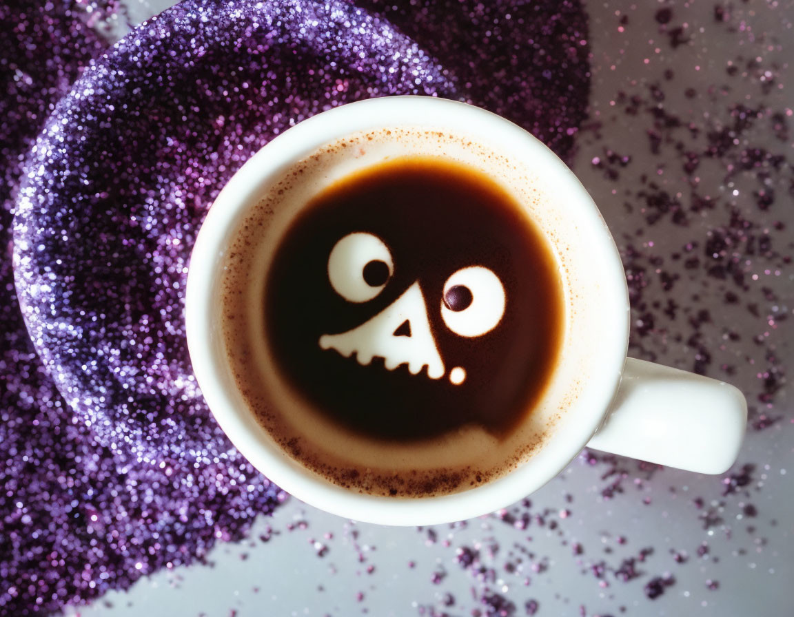 Skull-shaped foam art on a coffee cup with purple and silver glitter