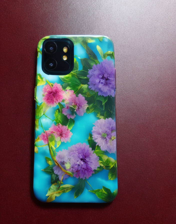 Smartphone with pink and purple floral case on blue backdrop and maroon surface