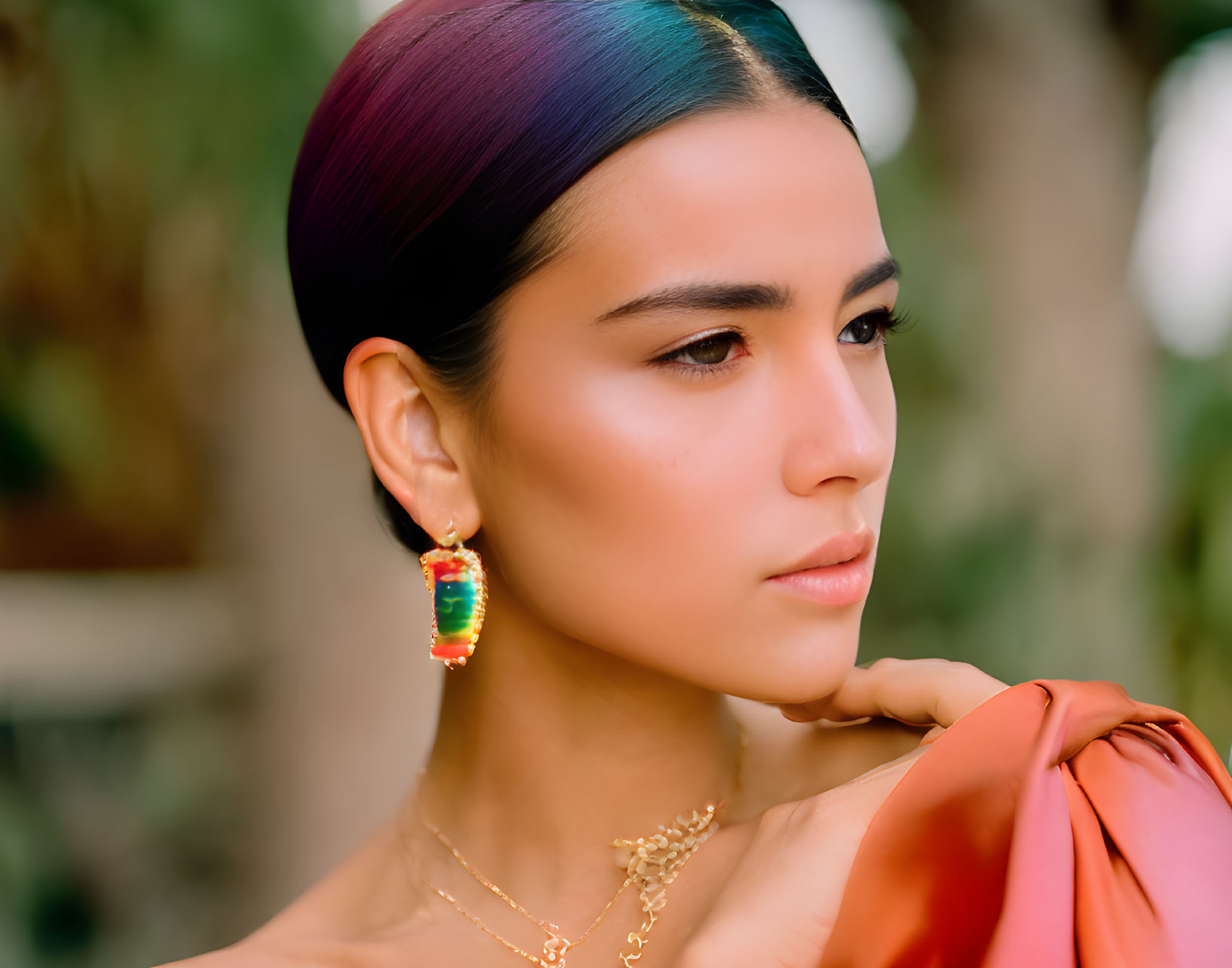 Rainbow-haired woman with gold earrings on green background