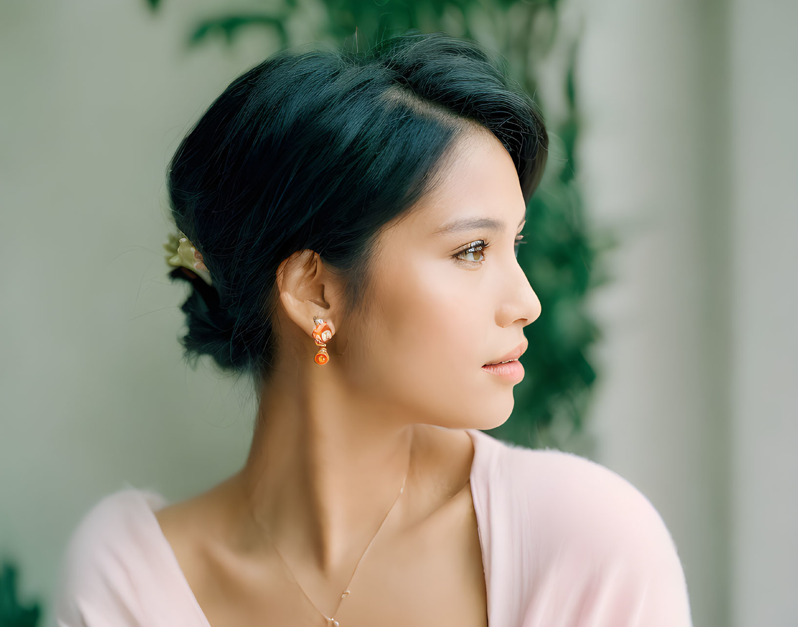 Woman with Flower in Hair Wearing Blush Top and Drop Earrings