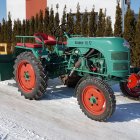 Vintage green tractor in snowy forest emitting exhaust fumes