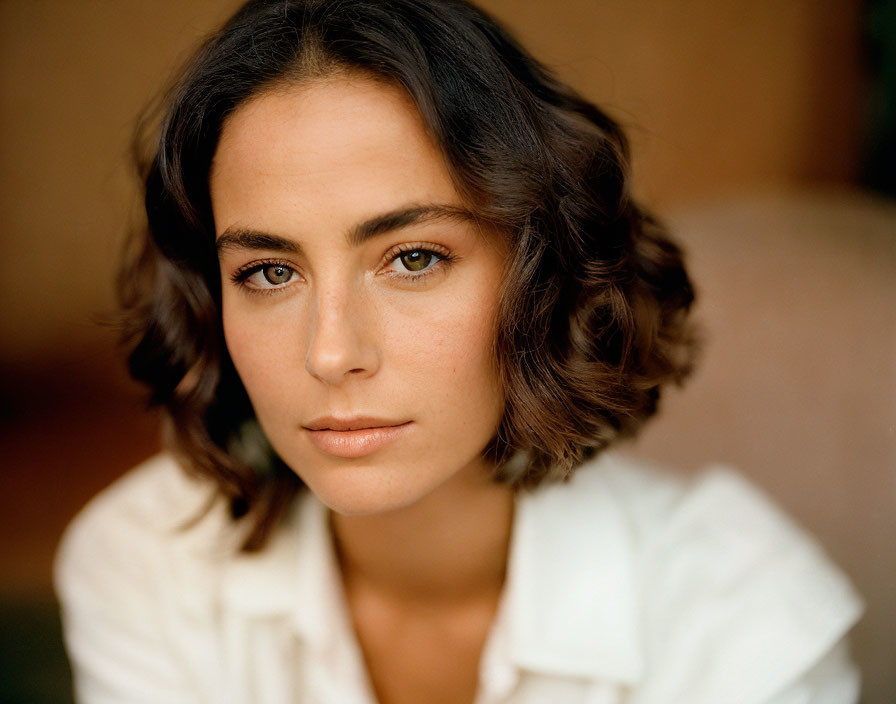 Portrait of woman with short wavy hair and hazel eyes in white shirt