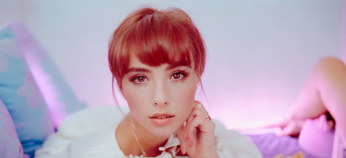 Portrait of woman with brown hair and bangs against pastel background