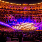 Historic amphitheater evening concert with musicians under violet light