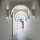 White Arched Corridor Leading to Courtyard with Bell Tower and Blue Skies