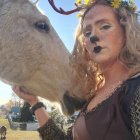 Fantasy-inspired woman with golden headdress and majestic unicorns in blooming field