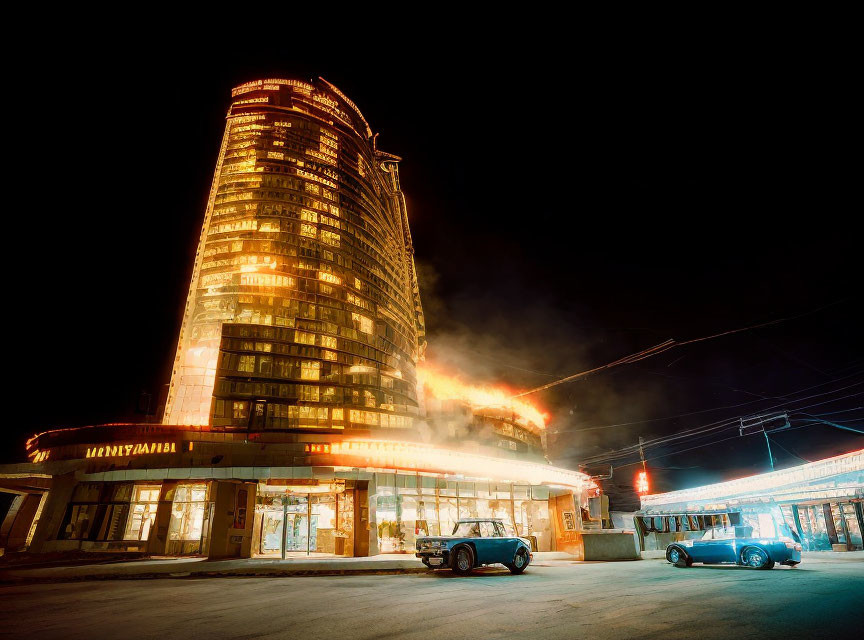 Night scene of illuminated building with steam and vintage cars.