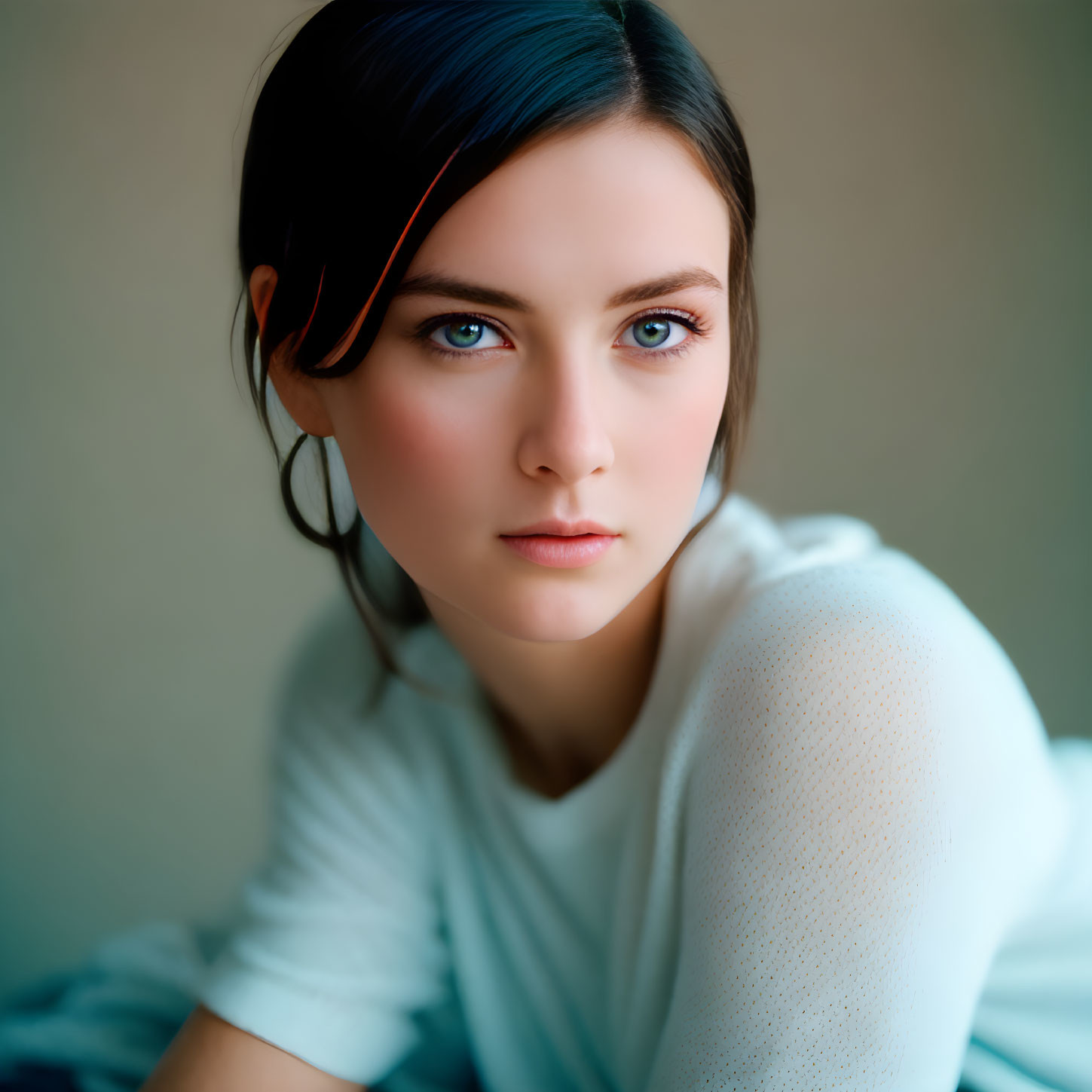 Dark-haired woman in white top and red hair clip, with blue eyes, staring at camera