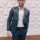 Stylish man in blue blazer on rocky path with cloudy sky