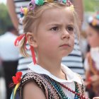 Woman in floral crown and patterned outfit gazes dreamily in soft natural light.