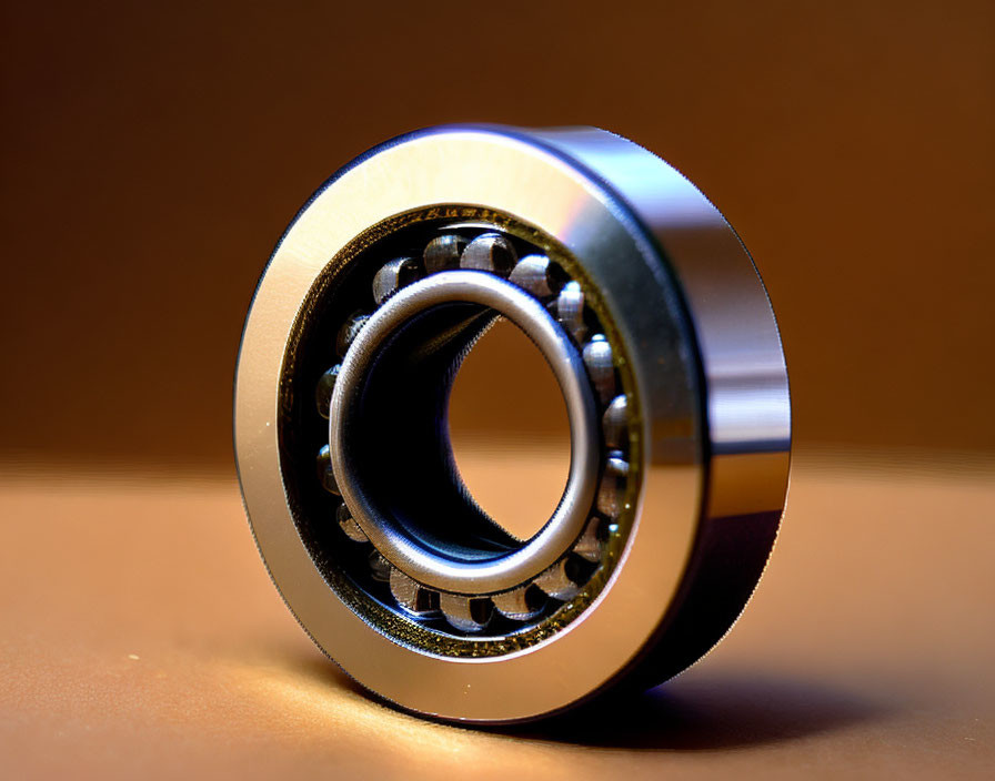 Shiny metal ball bearing on brown surface with soft lighting