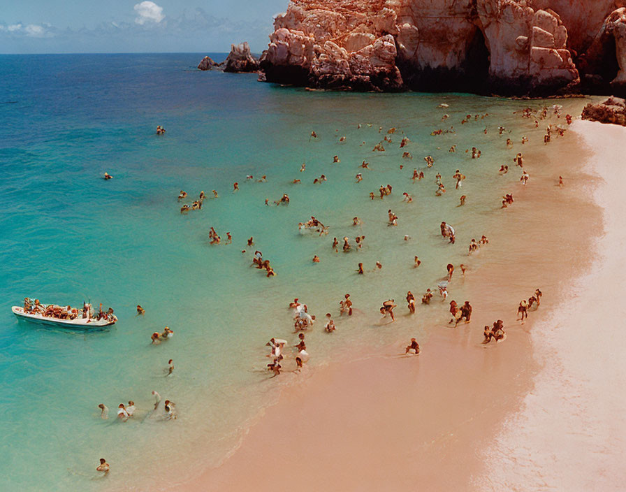 Sunlit Beach Scene with Clear Blue Waters and Swimmers Near Rocky Cliffs